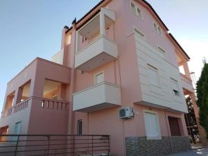 een roze gebouw met balkons aan de zijkant bij Treasures B&B in Paloúkia