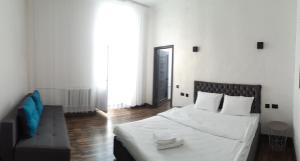 ヴィーンヌィツャにあるLUX Apartmentsの白いベッドルーム(ベッド1台、ソファ付)