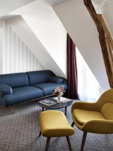 a living room with a blue couch and two chairs at Hotel Paradis in Paris