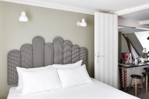 a bedroom with a white bed with a large headboard at Hotel Paradis in Paris