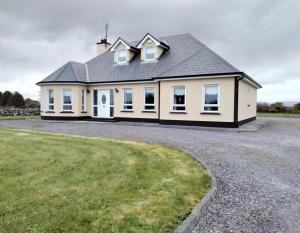 a large white house with a gravel driveway at Warm and welcoming family home in Ballinrobe