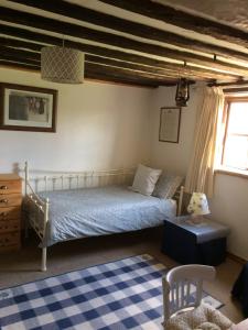Schlafzimmer mit einem Bett und einem blauen und weißen Teppich in der Unterkunft Dairy Cottage in Cockley Cley