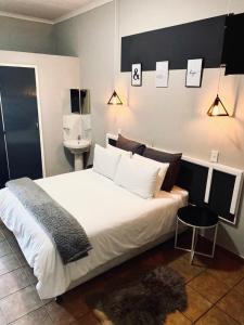 VnA Guesthouse في نيوكاسل: غرفة نوم بسرير ابيض كبير ومغسلة