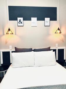 VnA Guesthouse في نيوكاسل: غرفة نوم بسرير ابيض مع صور على الحائط