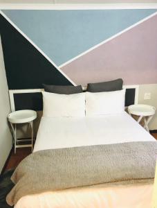 1 dormitorio con 1 cama grande y 2 taburetes en VnA Guesthouse, en Newcastle