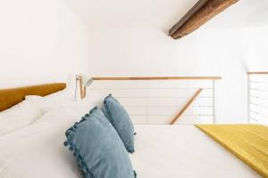 een slaapkamer met een wit bed met blauwe kussens bij iFlat Yellow Monti Studio Apartment in Rome