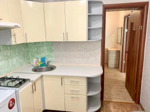 een keuken met witte kasten, een wastafel en een fornuis bij Аппартаменты в самом центре Площадь-Вал in Chernihiv