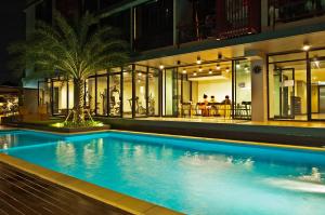 a swimming pool in front of a house at night at Grand Marina Residence Hotel in Ban Laem Chabang