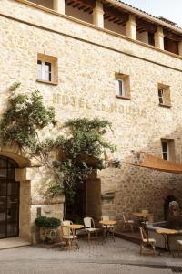 a large brick building with a table and chairs in front of it at Le Moulin, a Beaumier hotel in Lourmarin