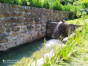 a retaining wall with a water fountain in a garden at Casas Vale Martinho in Santa Comba Dão