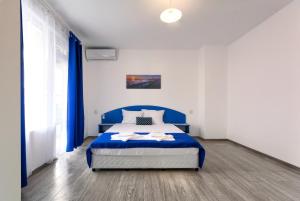 a bedroom with a blue bed and blue curtains at Siyanie Kiten in Kiten