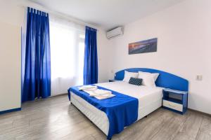 a bedroom with a blue and white bed with blue curtains at Siyanie Kiten in Kiten