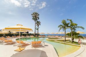 a pool with chairs and an umbrella and palm trees at NEXT - by Savoy Signature in Funchal