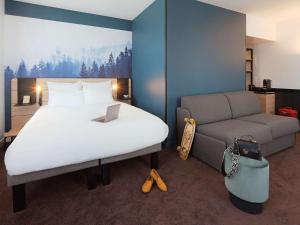 a hotel room with a bed and a couch at Novotel Annemasse Centre - Porte de Genève in Annemasse