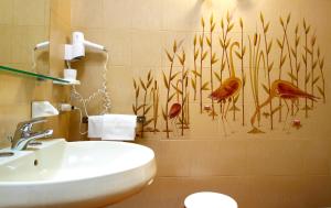 La salle de bains est pourvue d'un lavabo et d'oiseaux sur le mur. dans l'établissement Albergo La Quiete, à Desenzano del Garda