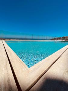a swimming pool with blue water and a bridge in the background at Hotel VIU57 in Mellieħa