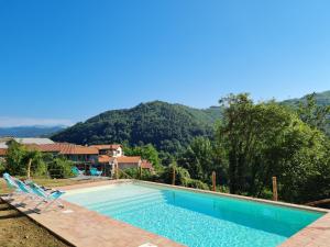 una piscina con sillas y montañas en el fondo en Le Case Nel Borgo, en Fivizzano