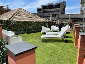 a patio with white chairs and grass on a roof at DOMUS FIESCHI Rooms self check in in Genova