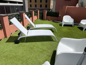 a row of white chairs sitting on top of grass at DOMUS FIESCHI Rooms self check in in Genova