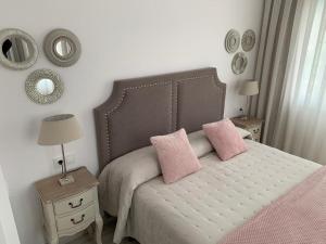 una camera con un letto con due cuscini rosa di Apartamento Los Arcos a Llanes