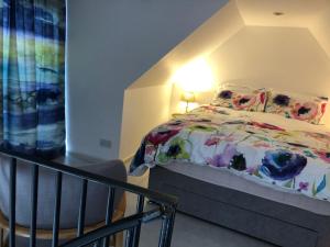 1 dormitorio con cama, lámpara y silla en Plumtree Cottage, en Kelso