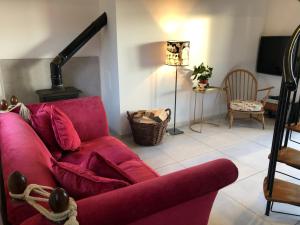 a living room with a red couch and a lamp at Plumtree Cottage in Kelso