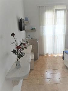 una habitación con una mesa con un jarrón con una flor en Katerina Rooms, en Tinos