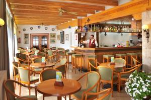 トッサ・デ・マールにあるHotel GHT Neptuno-Tossa & Venus SPAのテーブル付きのレストラン、バーの裏手にバーテンダー