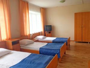 a hotel room with three beds and a television at Отель "Курган" in Kurgan