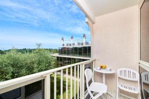 a balcony with two white chairs and a table at Hotel Istra Plava Laguna in Poreč