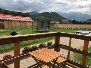 a wooden deck with a bench and a playground at Casute la munte in Râşnov