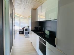 a kitchen with white cabinets and black counter tops at Voralpen Lodge - Ferienhaus mit Gym, Sauna & Hot Tub in Traisen +13 photos