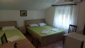 a bedroom with two beds and a table and a window at Apartmani Nino in Star Dojran