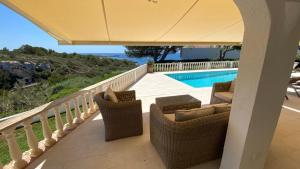 a balcony with wicker chairs and a swimming pool at Villa HERMITAGE in Binissafuller