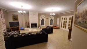 a living room with a black couch and a tv at "Kasneci Residence" Countryside Villa with a pool in Tirana