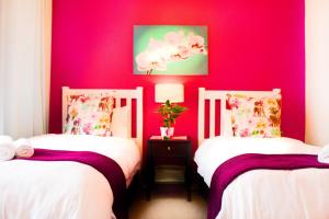 two beds in a room with a red wall at Fuhri Road Apartments Madison House in Alberton +156 photos