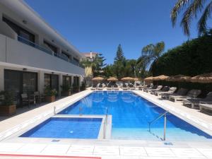 a swimming pool with chairs and a hotel at Paradise Hotel & Bar in Planos