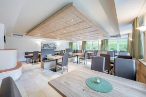 een eetkamer met tafels, stoelen en ramen bij Alpenhotel Zimba in Brand