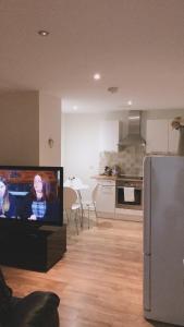 ein Wohnzimmer mit einem TV und einer Küche in der Unterkunft Heart Of Aberdeen City Centre 3 Bedrooms Apartment in Aberdeen