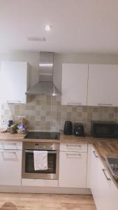 a kitchen with white cabinets and a stove top oven at Heart Of Aberdeen City Centre 3 Bedrooms Apartment in Aberdeen