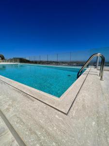 a swimming pool with a metal hand rail next to the ocean at Hotel VIU57 in Mellieħa