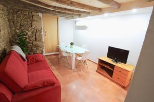a living room with a red couch and a tv at Duplex en planta baja junto a la catedral in Tarragona