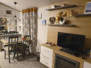 ein Wohnzimmer mit einem TV und einem Tisch mit Stühlen in der Unterkunft Devon holiday in Goodrington