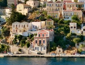 a cluster of houses on a hill next to the water at 1900 Hotel in Symi