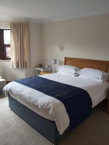 a bedroom with a large bed with blue and white sheets at Byerley House in Newmarket