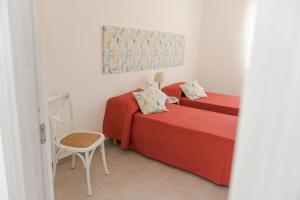 オロゼーイにあるCasa Lory - Appartamento con 2 camere in centro abitatoのベッドルーム1室(赤いシーツと椅子付きのベッド2台付)