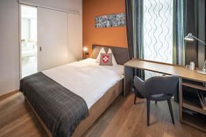 een slaapkamer met een bed, een bureau en een stoel bij Hotel Bären am Bundesplatz in Bern