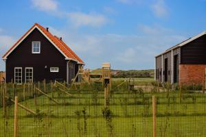a black house and a barn in a field at Hof Babel in Domburg