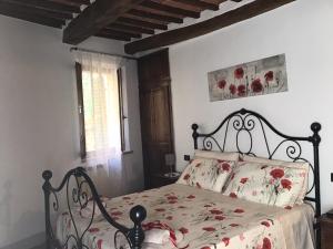 um quarto com uma cama com flores vermelhas em La casina in Via Fiorita em Montepulciano