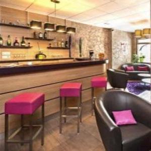 a bar with pink stools in front of a counter at Logis Hotel Restaurant des Voyageurs in Le Malzieu-Ville